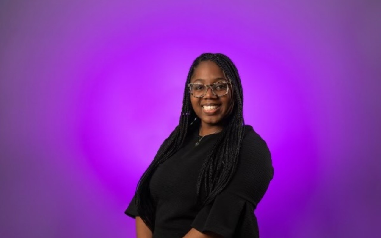woman smiling against purple background.