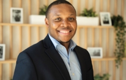 man smiling in suit jacket and collared shirt.