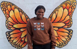 Woman Smiling in front of butterfly mural