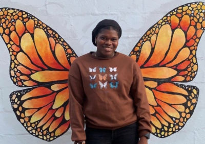 Woman Smiling in front of butterfly mural