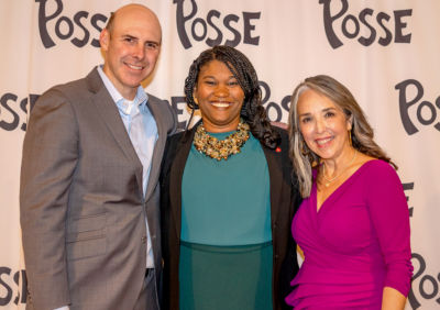 Three people smiling in front of a step and repeat