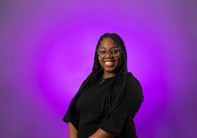 woman smiling against purple background.